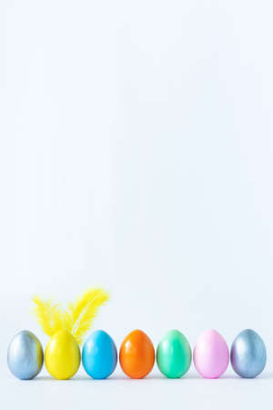 Top view of an easter composition of painted eggs in bright juicy colors on a white background with feather rabbit ears. Vacation concept, flat design, minimalismの写真素材