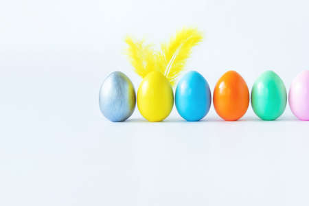 Top view of an easter composition of painted eggs in bright juicy colors on a white background with feather rabbit ears. Vacation concept, flat design, minimalismの写真素材