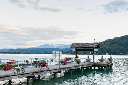 View of a wooden pier decorated with fresh flowers on a lake on a background of mountains in the evening at sunset. Concept landscape, background.の写真素材
