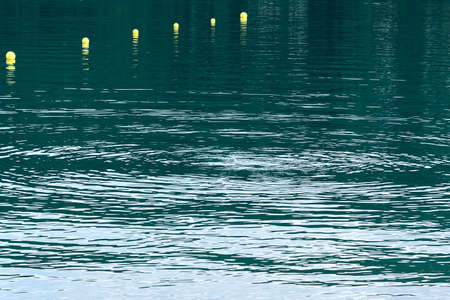 Turquoise water view with yellow buoys of a mountain lake. Concept landscape, background