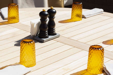 View of the served wooden table on which are glass glasses, napkins, salt and pepper. Concept...