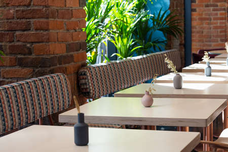 View of a number of empty tables in a cafe on a background of a brick wall and palm trees. Concept interior, business, quarantineの写真素材