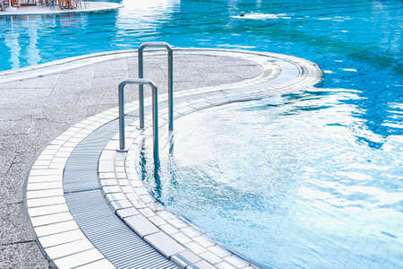 View of the pool in which a person is swimming on the background of a lawn with sunbeds, aqua slides and a street cafe. The concept of summer, vacation, spa, water park, travel, recovery, sportの写真素材