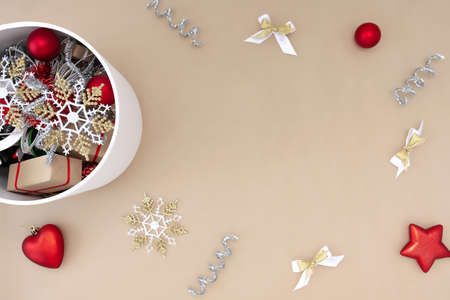 A white round box with Christmas toys next to which are decorations of red, white, gold and silver on a beige backgroundの写真素材