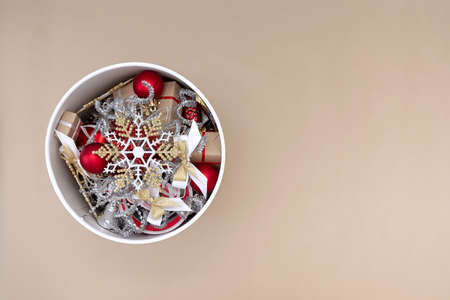 White round box with Christmas decorations in red, white, gold and silver on a beige backgroundの写真素材