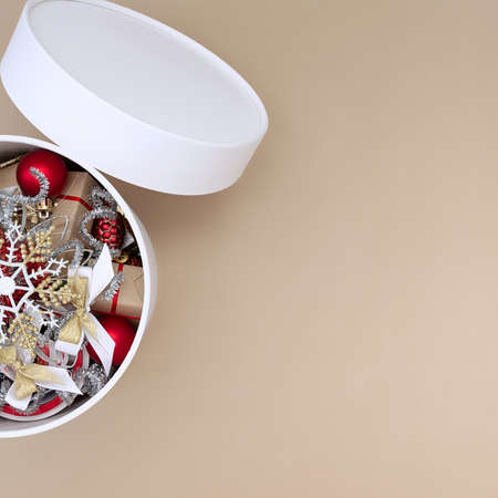 White round box with Christmas decorations in red, white, gold and silver on a beige backgroundの写真素材