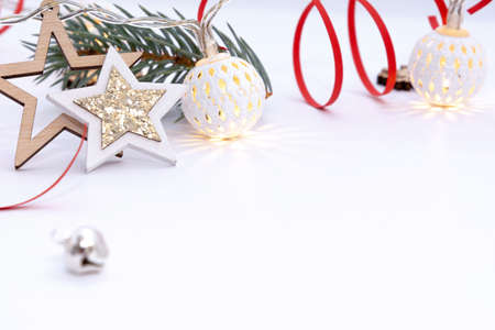 Christmas composition of wooden stars with sparkles, garlands of white luminous balls, fir branches and red ribbons on a white backgroundの写真素材