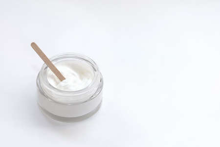 Glass jar with cream and a wooden stick made at home to nourish the skinの写真素材