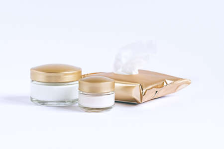 Glass jars with different creams and cleaning wipes for facial skin care on a white backgroundの写真素材