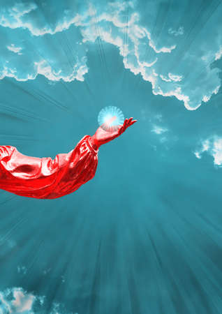 Contemporary collage. A red hand on a background of a dark blue sky with clouds in which a glowing ball lies.の写真素材