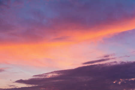 View of the sky in the evening at sunset with a dark cloud and bright orange glow from the sun. Landscape concept, backgroundの写真素材