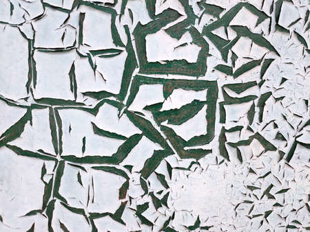 The texture of the painted wall with peeling white paint which is covered with large green cracks. Concept background, textureの写真素材