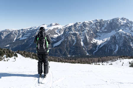 A man stands on the side of a mountain against the backdrop of the snow-capped Dolomites. Concept for sports, landscape, peopleの写真素材