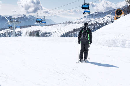 A man rides down the ski slope against the backdrop of snow-capped mountains and blue chair lifts .. The concept of sports, landscape, peopleの写真素材