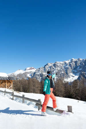 A woman in a colorful ski suit, helmet and sunglasses after skiing stands against the backdrop of mountain peaks. Sports concept, people, travelの写真素材