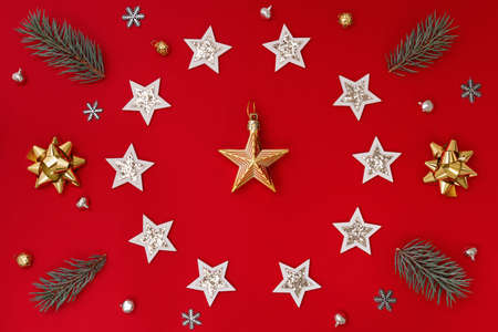 Flat composition of Christmas decorations in white and gold and fir branches on a red backgroundの写真素材