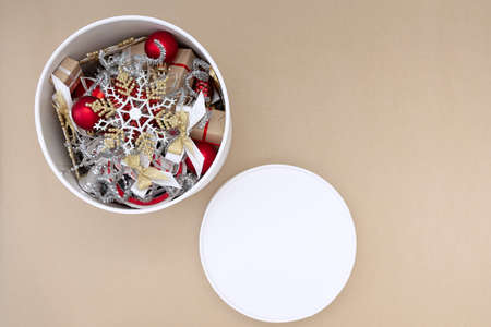 White round box with Christmas decorations in red, white, gold and silver on a beige backgroundの写真素材