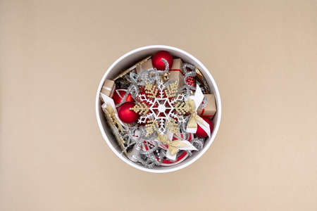 White round box with Christmas decorations in red, white, gold and silver on a beige backgroundの写真素材