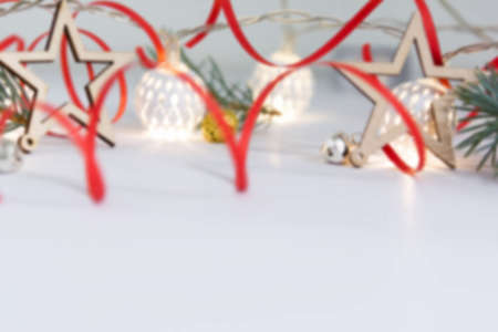 Christmas composition of fir branches, wooden stars, garlands of white luminous balls and red ribbon on a white backgroundの写真素材