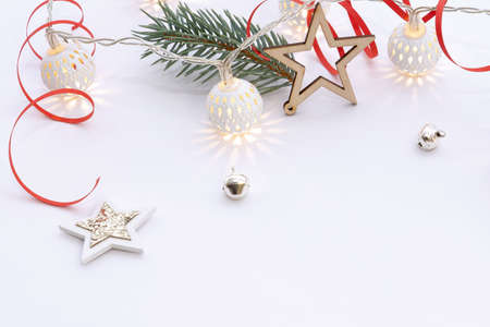 Christmas composition of wooden stars with sparkles, garlands of white luminous balls, fir branches and red ribbons on a white backgroundの写真素材