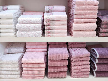 Terry towels of various colors are folded neatly on the shelves. Concept for lifestyle, retail, comfort.の写真素材