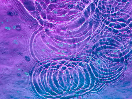Water texture with circular streaks on the surface, bubbles and sun glare. Concept background, texture, abstraction.の写真素材