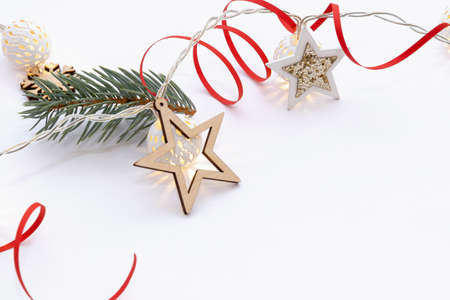 Christmas composition of wooden stars with sparkles, garlands of white luminous balls, fir branches and red ribbons on a white background.の写真素材