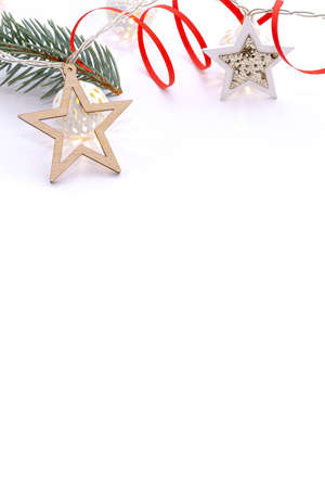 Christmas composition of fir branches, wooden stars, garlands of white luminous balls and red ribbon on a white background.の写真素材