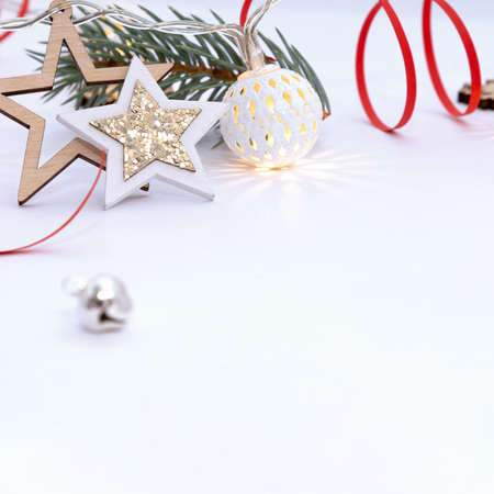 Christmas composition of wooden stars with sparkles, garlands of white luminous balls, fir branches and red ribbons on a white background.の写真素材