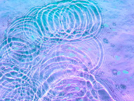 Water texture with circular streaks on the surface, bubbles and sun glare. Concept background, texture, abstraction.の写真素材