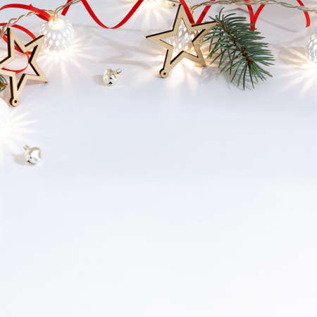 Christmas composition of wooden stars, a garland of white luminous balls, fir branches, bells and a red ribbon on a white backgroundの写真素材