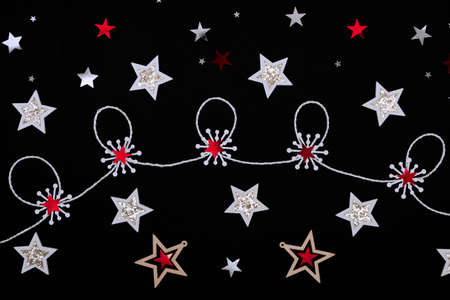 Christmas layout on a black background of multicolored stars, snowflakes and ribbons. Concept for christmas, holidays, backgroundの写真素材