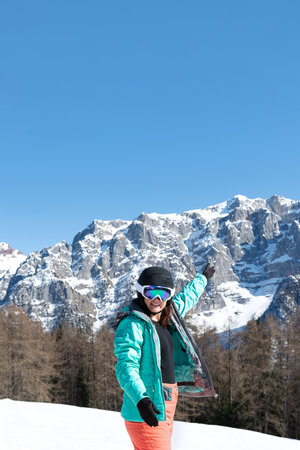 A woman in a colorful ski suit, helmet and sunglasses after skiing stands against the backdrop of mountain peaks. Sports concept, people, travelの写真素材
