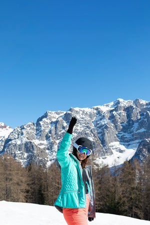 A woman in a colorful ski suit, helmet and sunglasses after skiing stands against the backdrop of mountain peaks. Sports concept, people, travelの写真素材