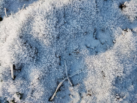 A view of the uneven surface of the earth covered with crystals of frost on a frosty sunny day.の写真素材