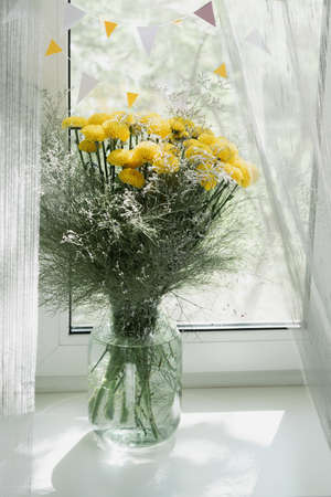 View of a bouquet of yellow chrysanthemums in a vase on the window. Concept background, flowers, holidayの写真素材