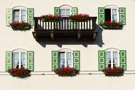 Building view with balcony and windows with green shutters decorated with flowersの写真素材