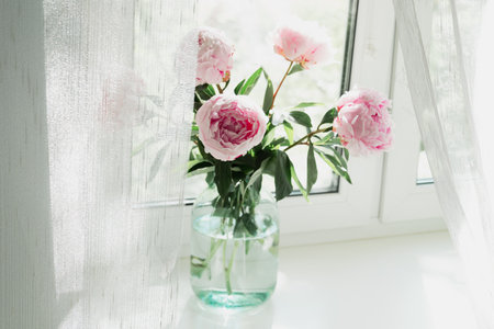 A view of a bouquet of pink peonies standing in a vase on the window. Concept background, flowers, holidayの写真素材