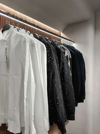 Rack with clothes on hangers in the store against the backdrop of a wallの写真素材