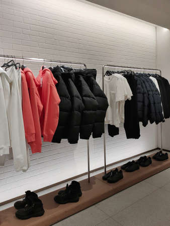 Rack with clothes on hangers and shoes in the storeの写真素材