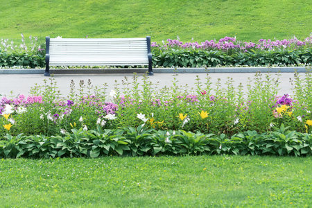 View of a flowerbed from different blooming flowers, lawn and shops in the city park.の写真素材
