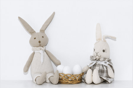 Easter composition with soft toys of hares and white eggs that are on the shelf in the roomの写真素材