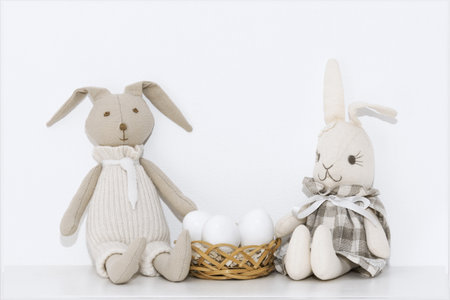 Easter composition with soft toys of hares and white eggs that are on the shelf in the roomの写真素材