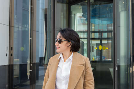 A beautiful woman comes out of the doors of a business center and smiles.の写真素材