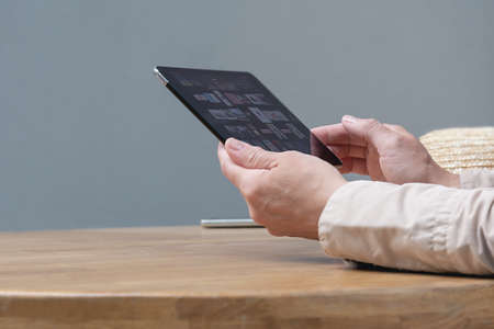 A woman is sitting at a table in a cafe with a tablet in her hands.の写真素材