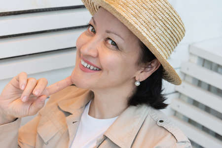Portrait of a smiling young woman in summer clothes and a straw hat sitting on the summer terrace of a cafe.の写真素材