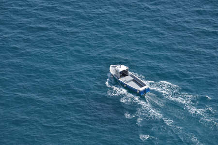 Aerial view of a white fishing boat on a blue clear sea waterの写真素材