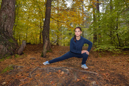 Energetic young woman do exercises outdoors in park to keep their bodies in shape. Fitness concept....