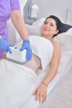 Pretty young woman getting cryolipolyse fat treatment in professional cosmetic cabinetの写真素材