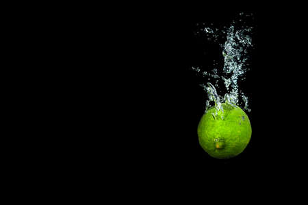 Fresh lime in water with air bubbles water splash isolated on blackの写真素材